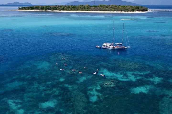 Aerial view of a sailboat and snorkelers near a beautiful tropical island